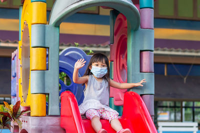 Full length of cute girl sitting on slide at playground