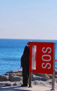 Close-up of sos sign against calm blue sea