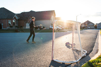 Full length of man playing soccer against sky