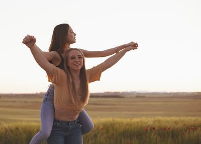 Two women holding hands at sunset in the field