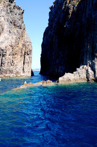 Rock formations in sea against blue sky