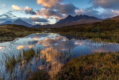 Scenic view of lake and mountains against dramatic sky