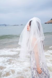 Side view of young bride wearing veil at beach
