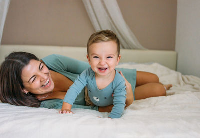 Mother and son enjoying on bed at home