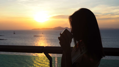 Silhouette woman drinking coffee during sunset