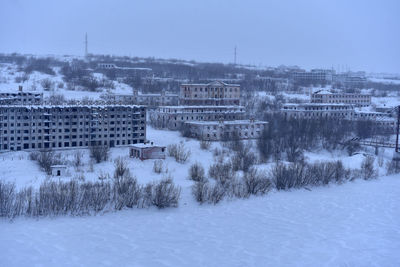 Buildings on snow covered land against sky