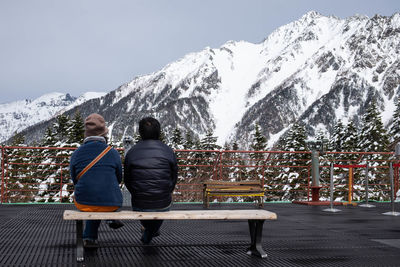 Rear view of people sitting on snowcapped mountain