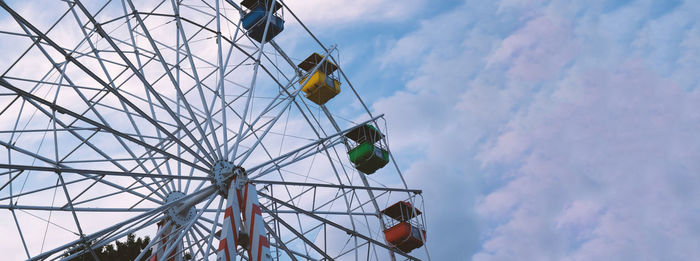 Colorful ferris wheels in the amusement park on a background of blue sky with clouds. 