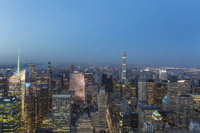 Illuminated cityscape against blue sky