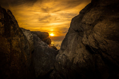 Close-up of cliff against dramatic sky during sunset