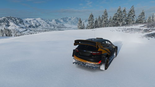 Car on snow covered mountains against sky