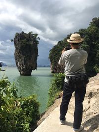 Rear view of man standing by plants against sky