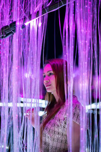 Portrait of beautiful young woman standing against pink wall