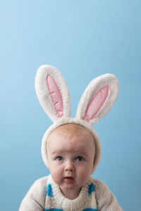 Low angle view of cute baby girl against blue background