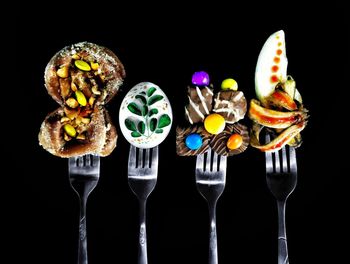 Close-up of forks with sweet food against black background