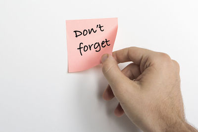Close-up of hand holding text against white background