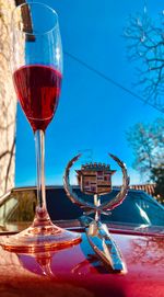 Close-up of wineglass on table against blue sky