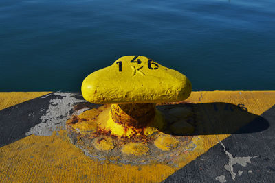 High angle view of yellow cleat on pier at beach