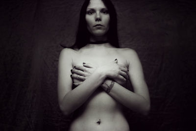 Portrait of young naked woman standing against wall