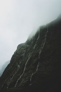 Low angle view of mountain against sky during foggy weather