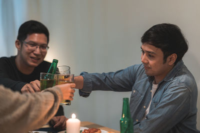 Portrait of young man with drink sitting on table