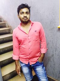 Portrait of young man standing against wall