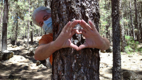 Midsection of father and daughter on tree trunk in forest