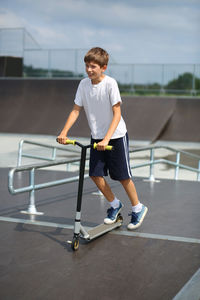 Active ten year old boy riding a scooter in the summer skate park