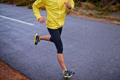 Low section of man skateboarding on road