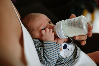 Midsection of woman feeding milk to newborn son