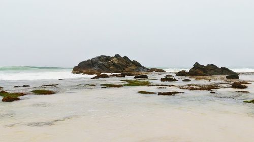 Rocks on beach against clear sky