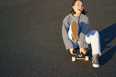 Portrait of young woman sitting on road