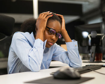 Side view of young woman using mobile phone in office