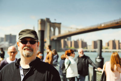 Portrait of young man with sunglasses against sky in city