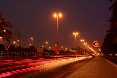 Light trails on road against sky at night