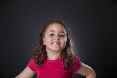 Portrait of smiling girl against black background