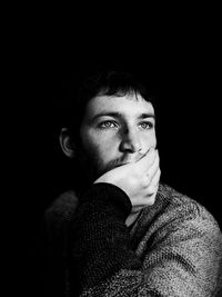 Portrait of young man against black background