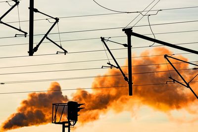 Low angle view of silhouette electricity pylon against sky during sunset