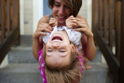 Happy mother playing with daughter while sitting on steps