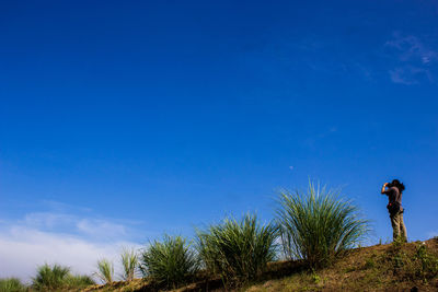 Low angle view of man standing against blue sky