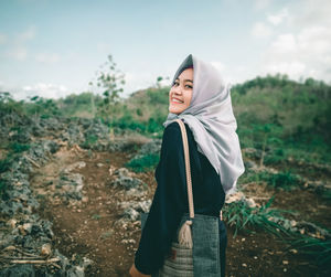 Portrait of young woman standing on field