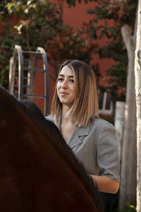 Young blonde woman with her brown horse enjoys a day on the farm.