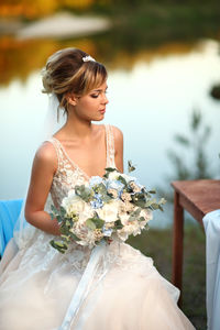 Bride with a bouquet of flowers on the background of the river