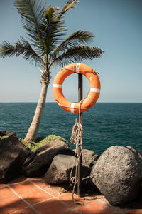 Rope on rock by sea against sky