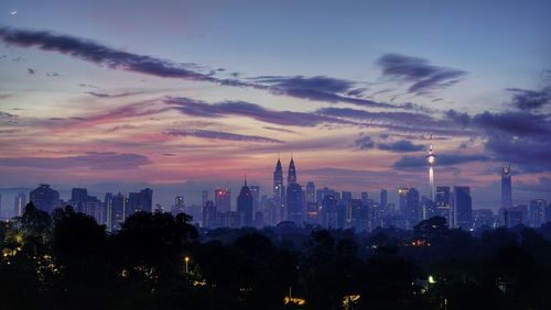 Silhouette illuminated city against sky during sunset