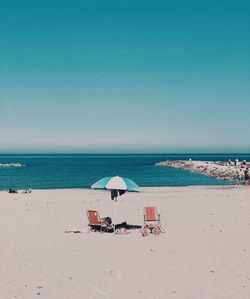 Deck chairs on beach against sky