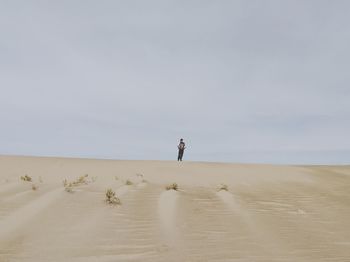 Man walking on sand dune in desert