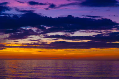 Scenic view of sea against dramatic sky during sunset