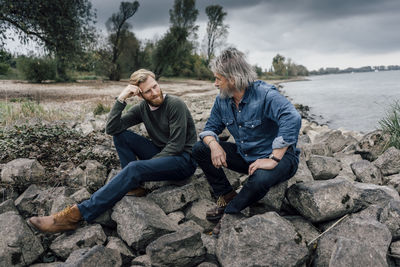 Father and son spending time together outdoors, taking a break, sitting on stones