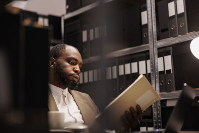 Side view of man using mobile phone while standing in office